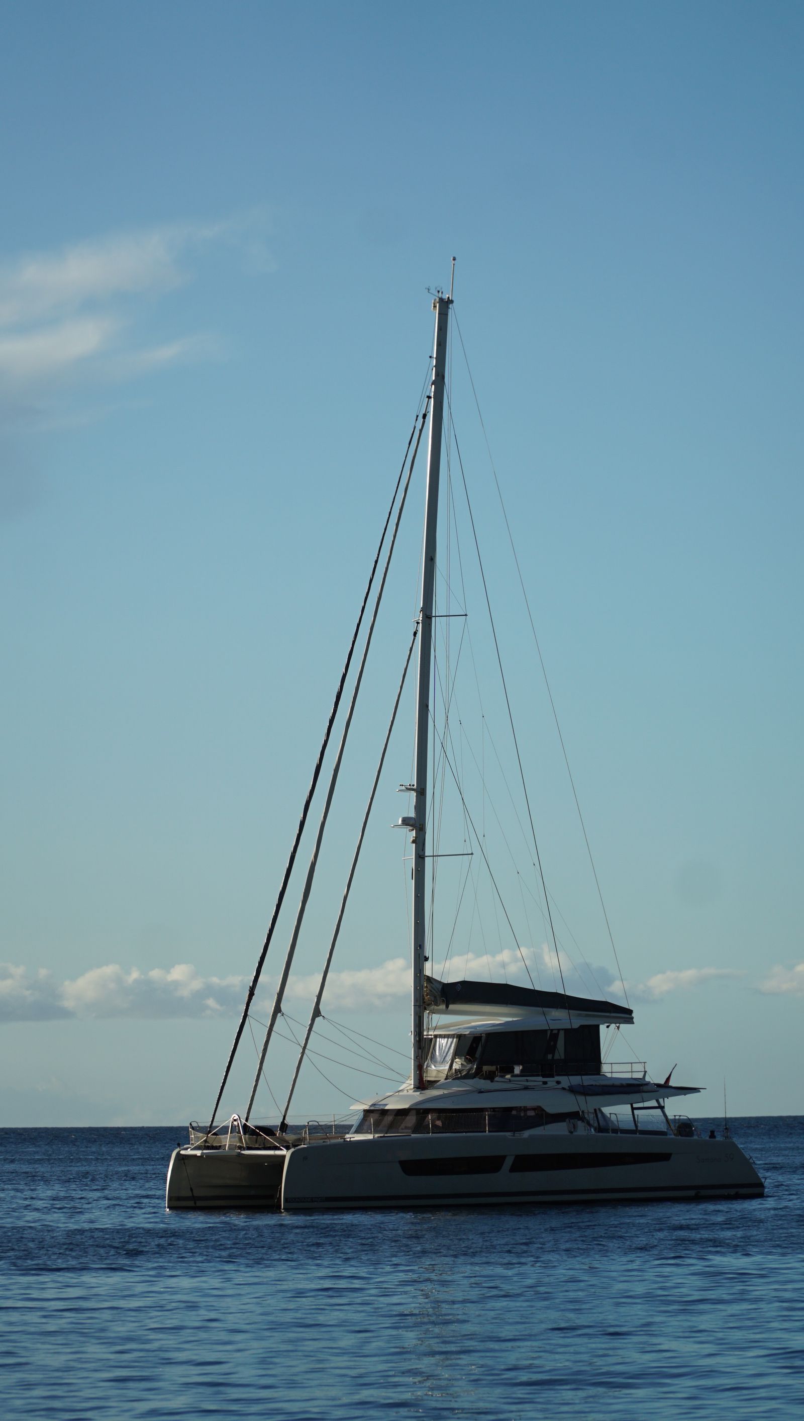 A catamaran sailing on calm turquoise water at sunset