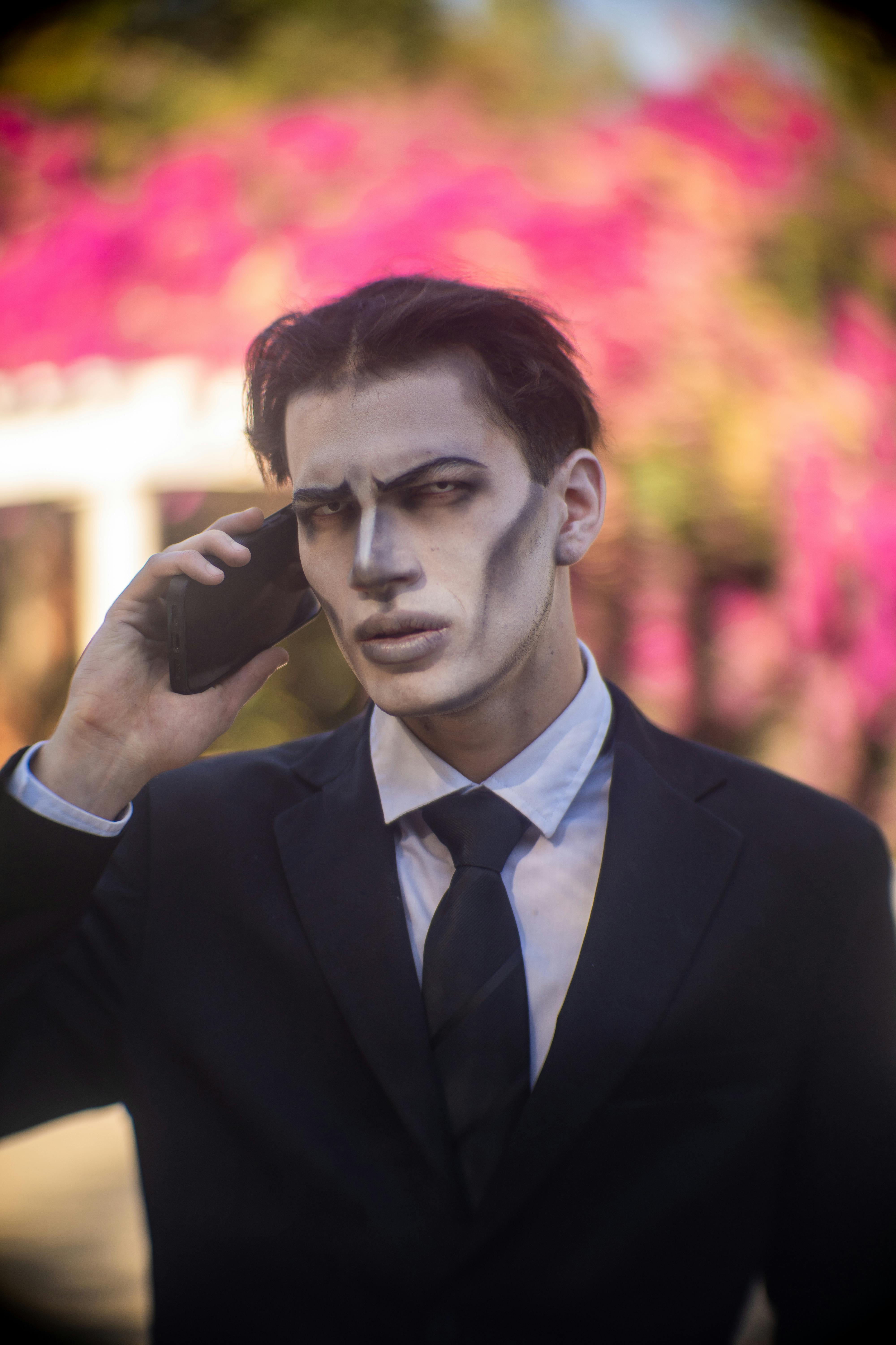 De franc Home de negocis macallà amb un vestit al telèfon amb maquillatge zombi a l'aire lliure vibrant. Foto d'estoc