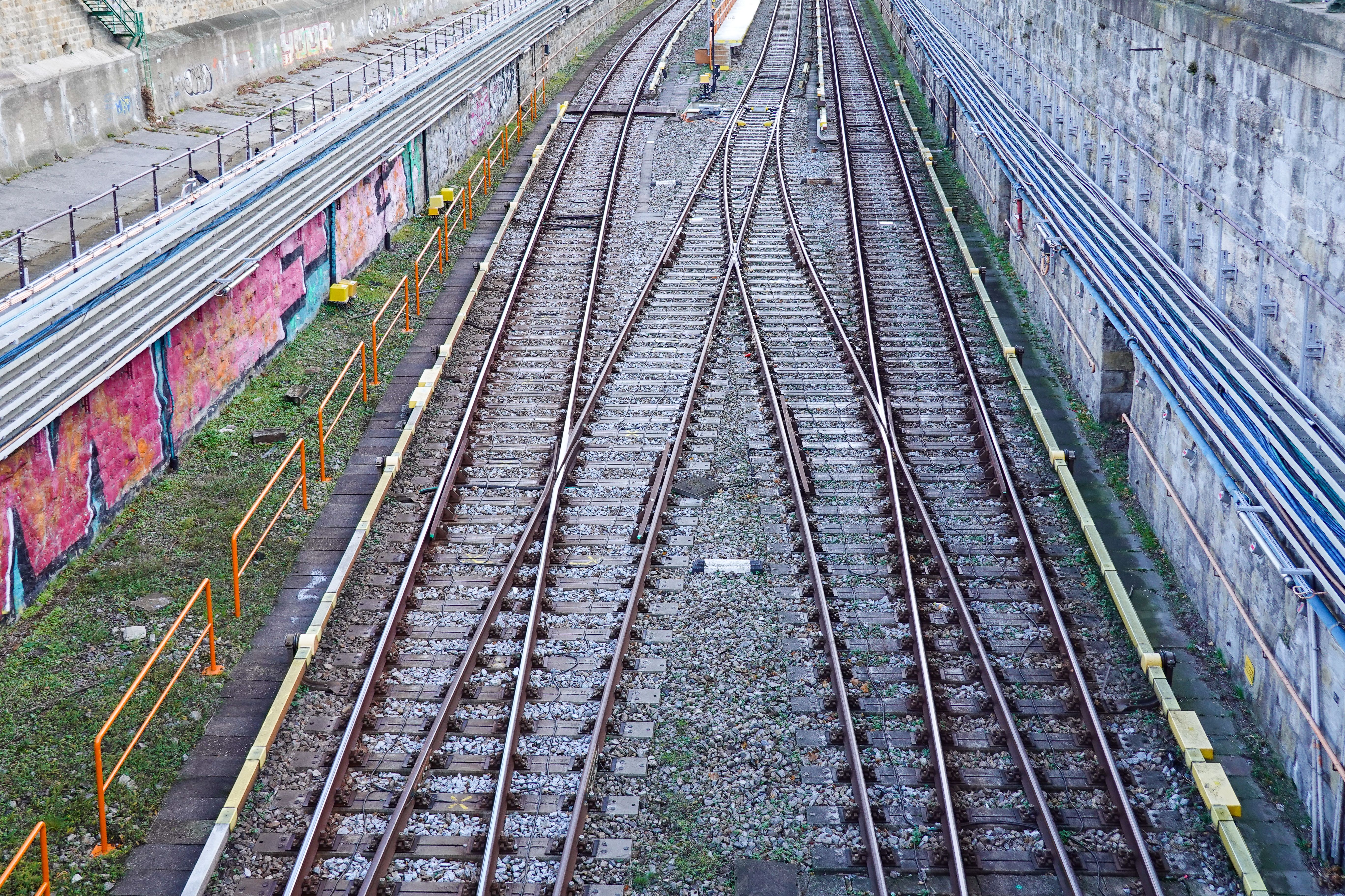 Aerial view of converging train tracks in an urban environment with colorful graffiti.