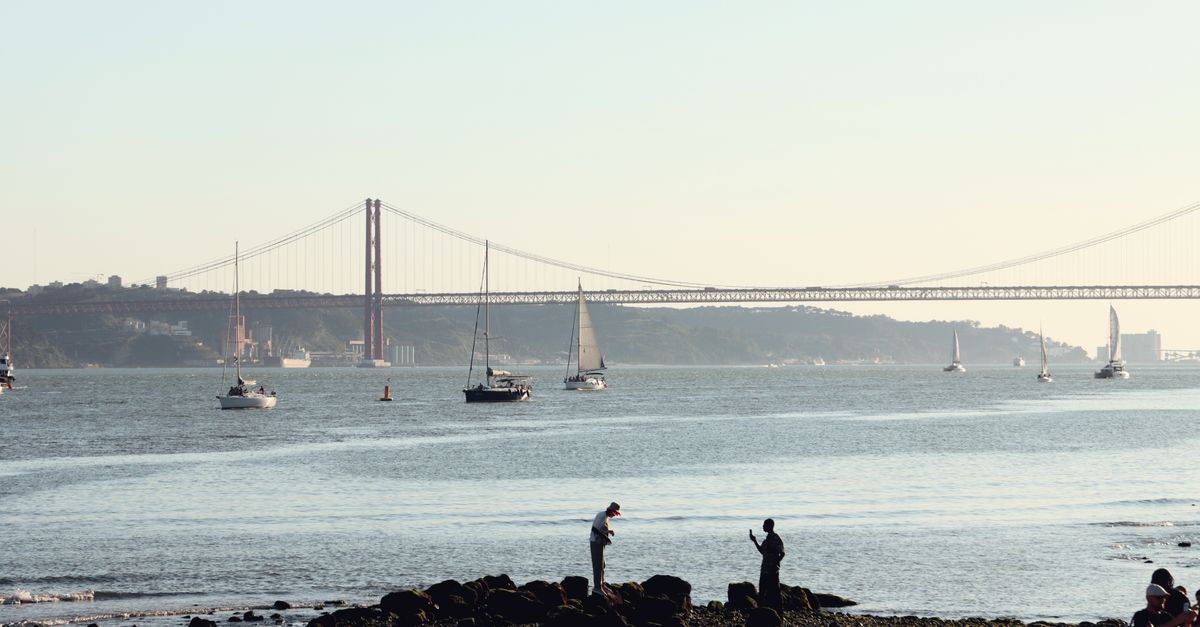 Sailboats near 25 de Abril Bridge in Lisbon on a sunny day. Perfect travel destination.