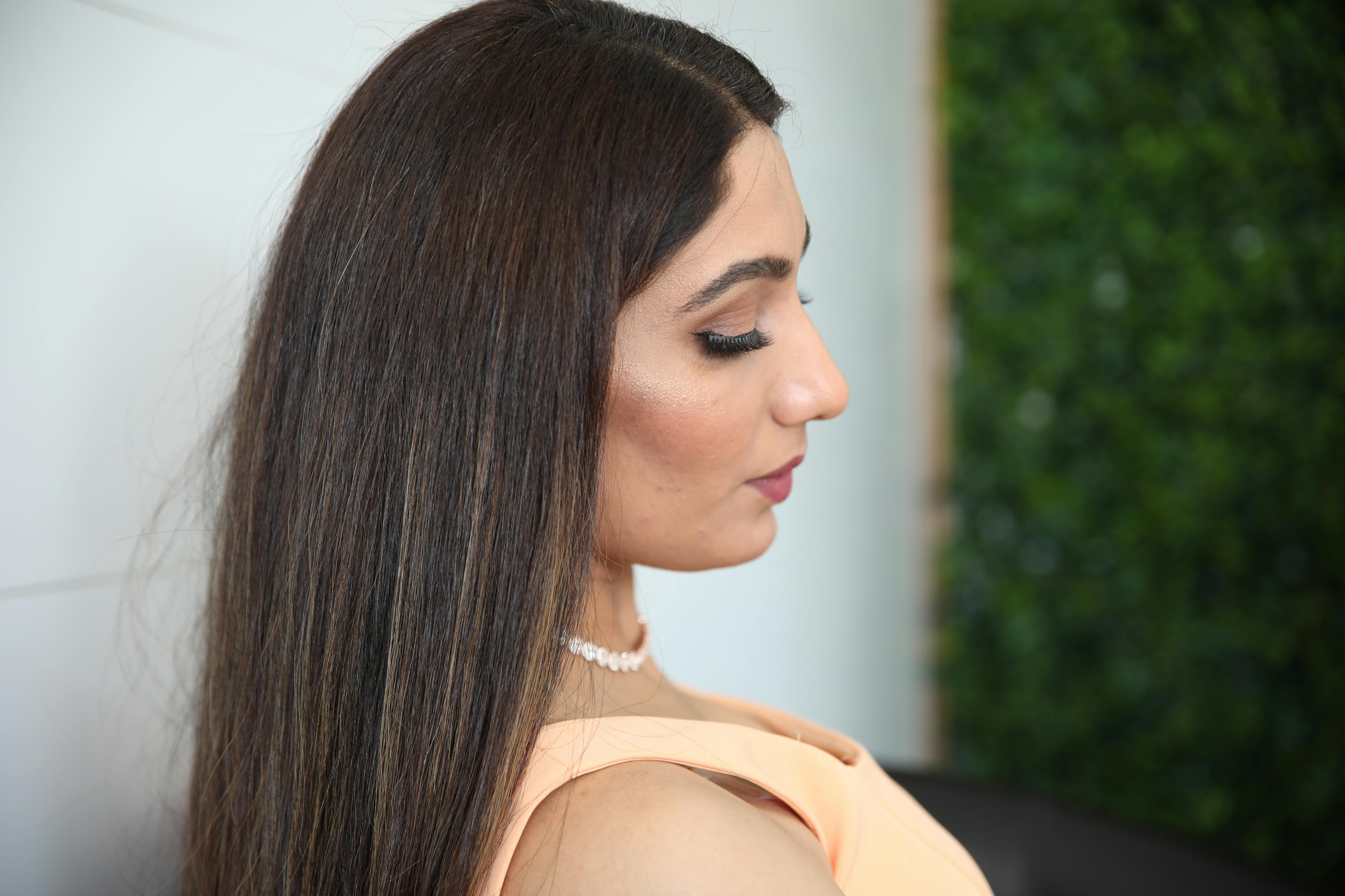 Profile portrait of an elegant woman with long hair and pearl necklace.