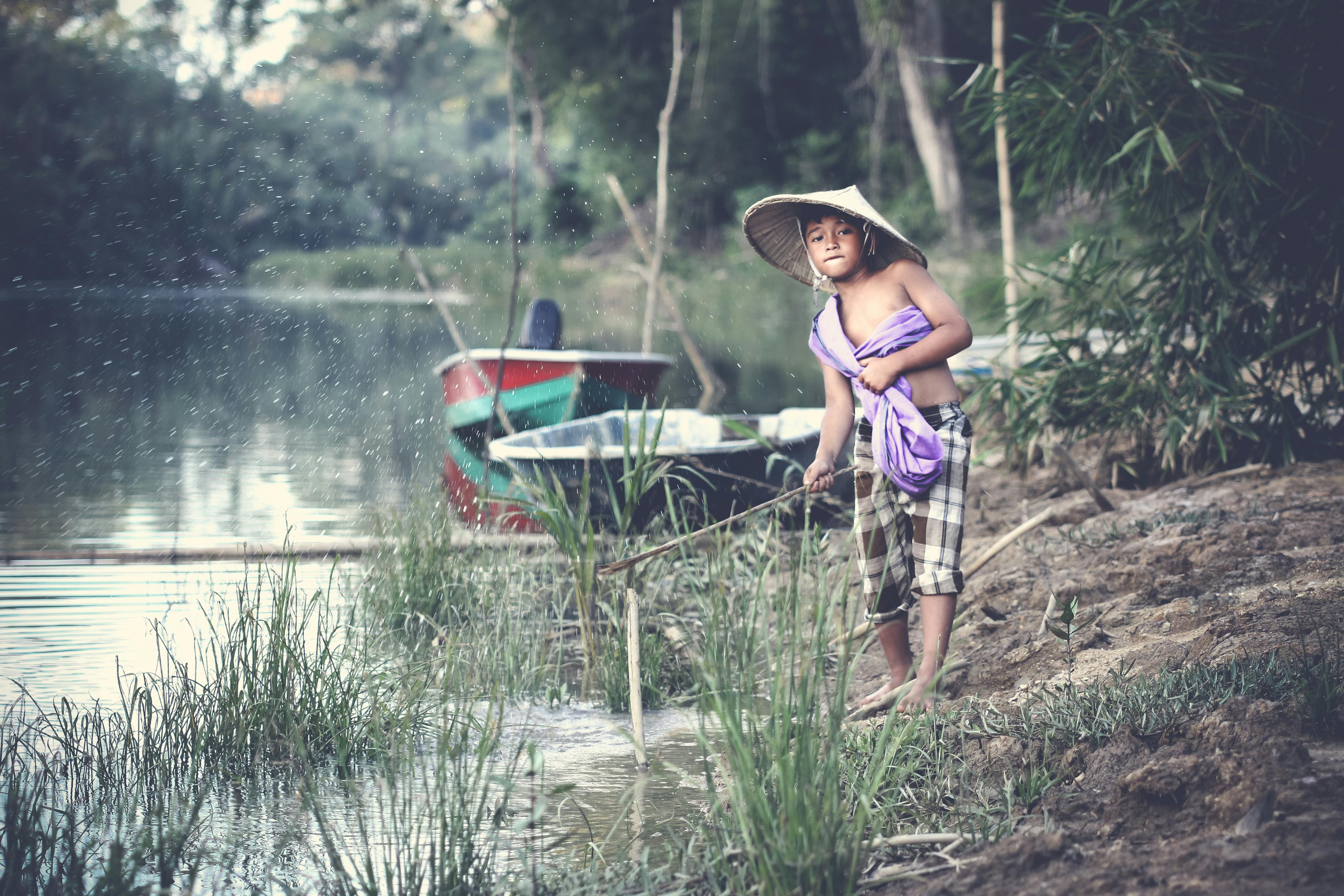 孩子们在河边乘船钓鱼，营造出宁静的户外景观