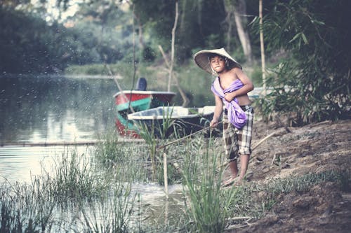 Boy Holding Stick at Side of River