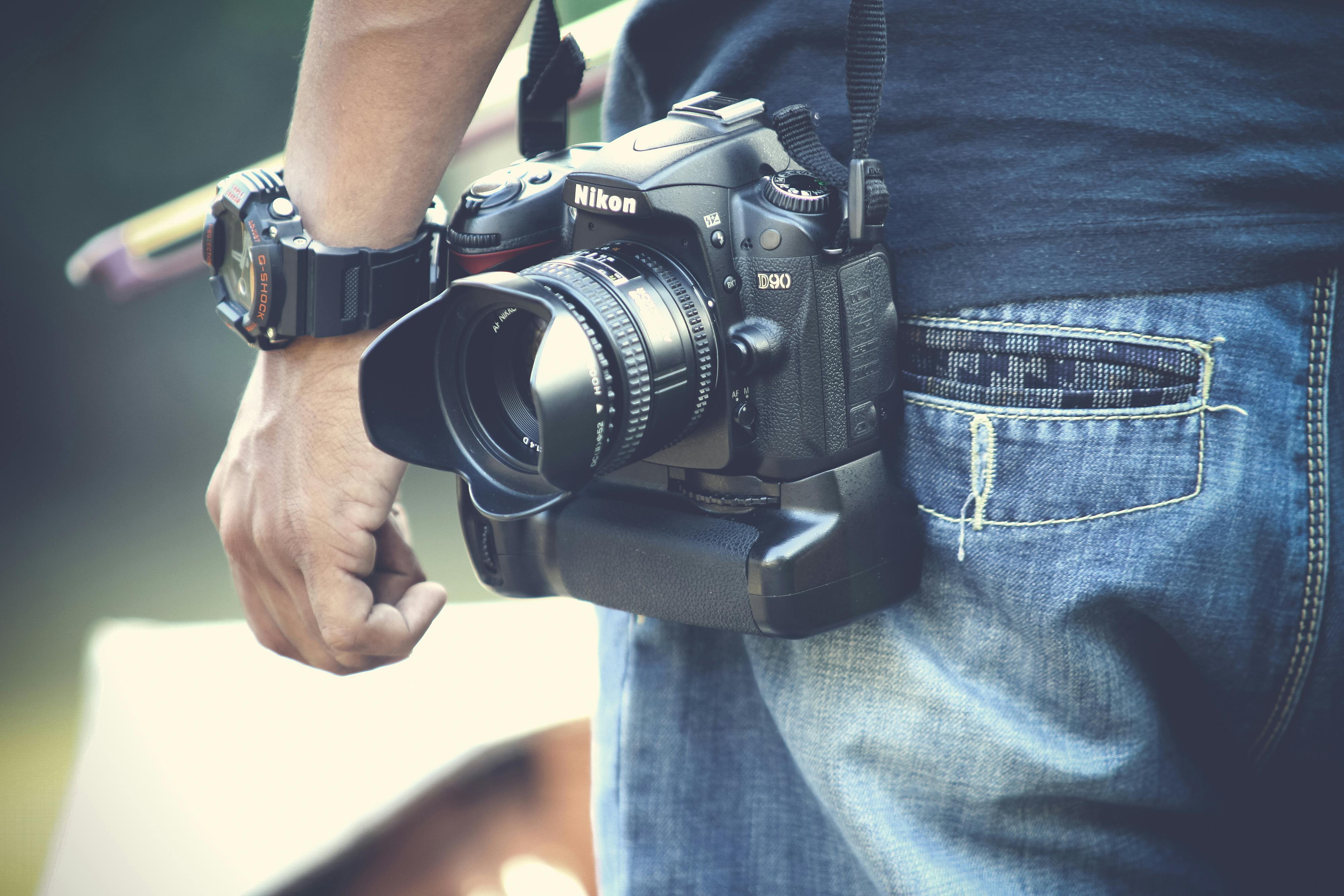 selective focus photography of man with black nikon dslr camera