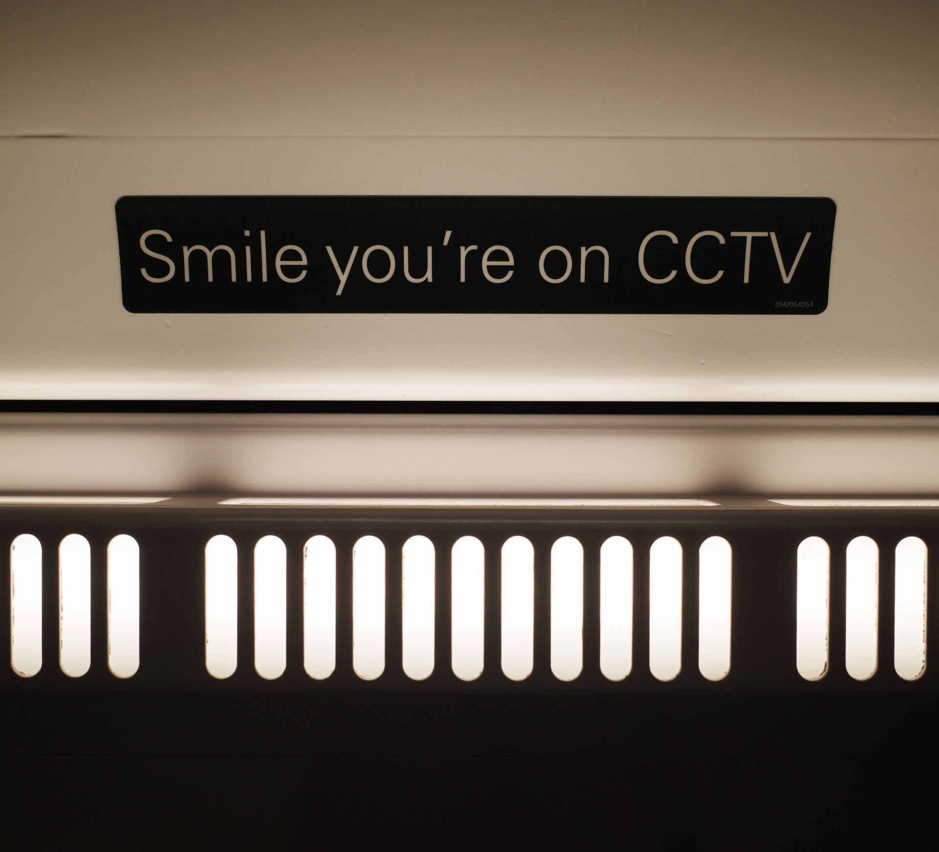 Close-up of a CCTV warning sign with unique interior lighting in a public space.