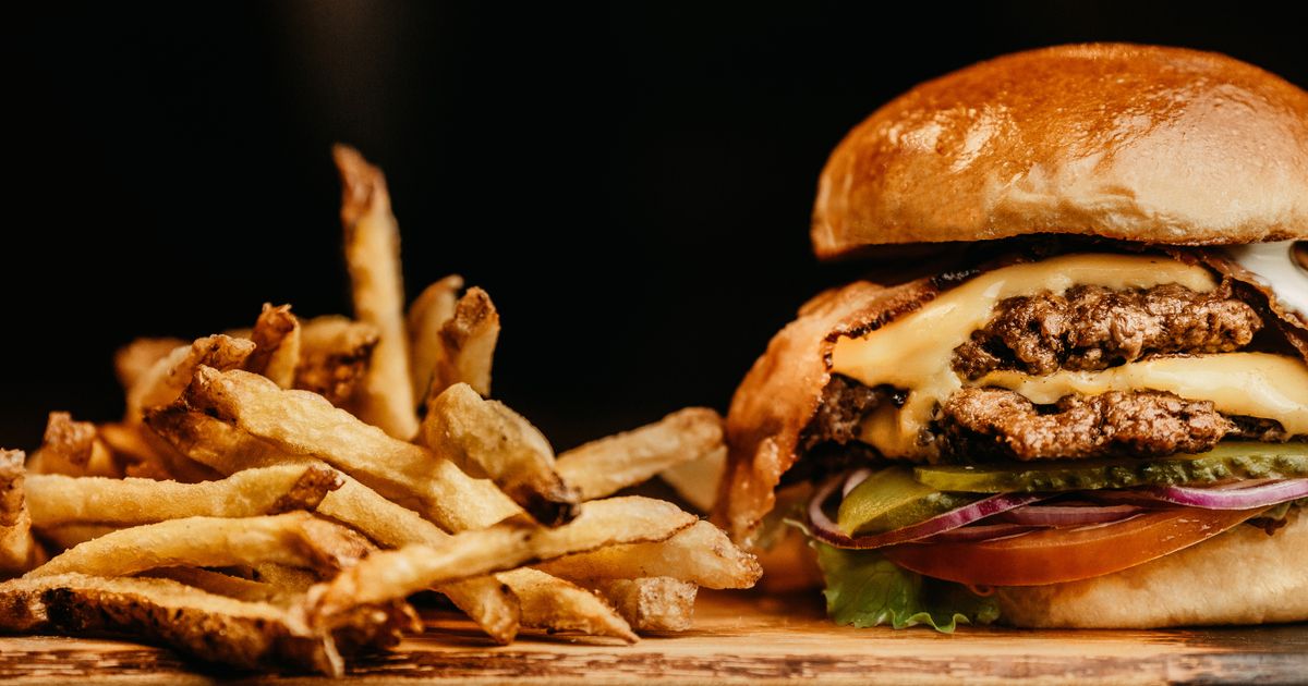 A cheeseburger and fries on a wooden board.