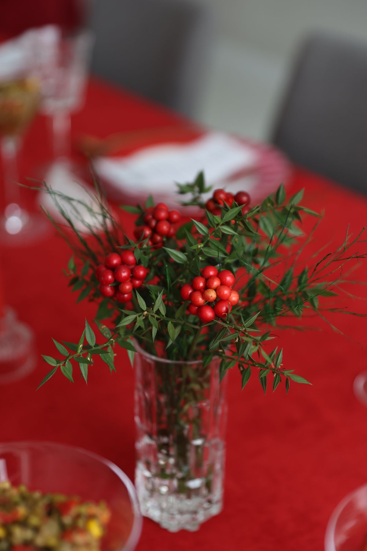 Red berry branches in a glass vase on a Christmas table