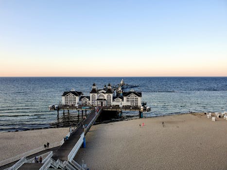 一座历史建筑矗立在海边码头上，周围环绕着原始的海滩和平静的水域，景色优美