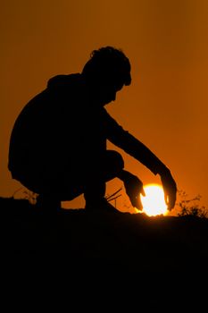 Silhouette of person at sunset in Vizianagaram, India, creatively interacting with the sun.