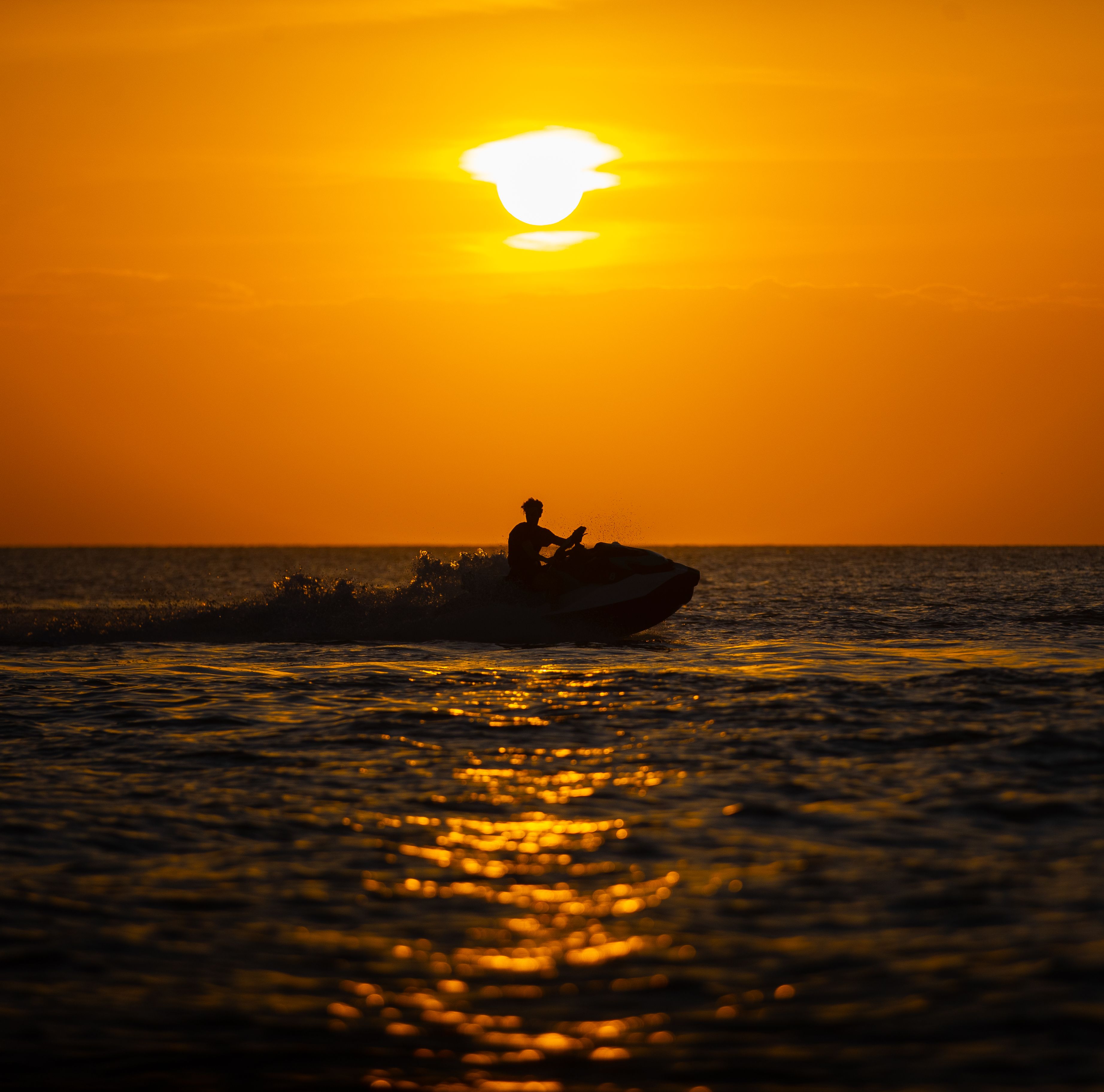 Silhouette of a jet ski riding at sunset in Zanzibar, Tanzania.