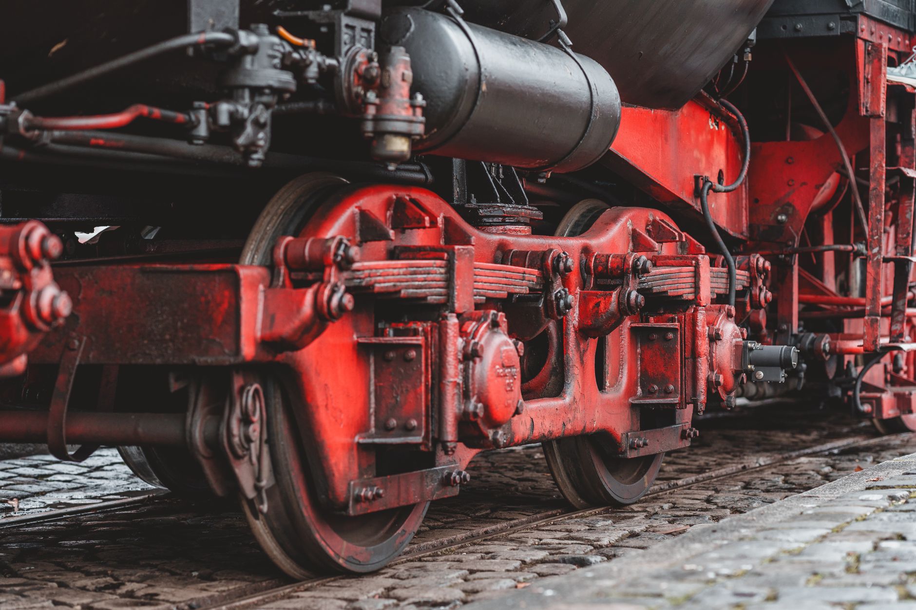 Detail shot of a vintage red steam locomotive showcasing its wheels and mechanical components.