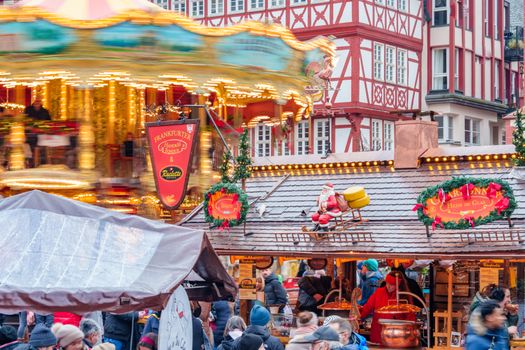 A vibrant scene at Frankfurt's Christmas market with people, carousel, and festive decorations.