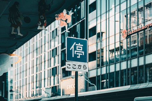 Japanese street sign in busy urban setting, reflecting modern architecture.