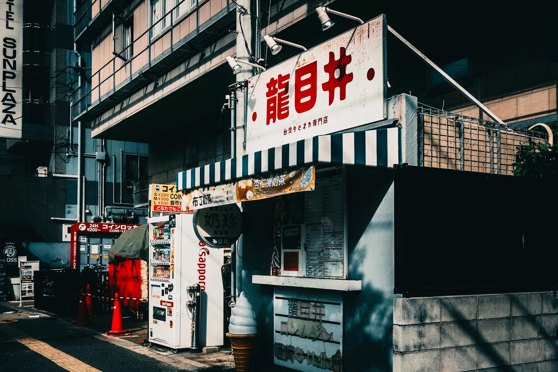 A bustling Japanese street corner featuring a vending machine and storefront in urban setting.