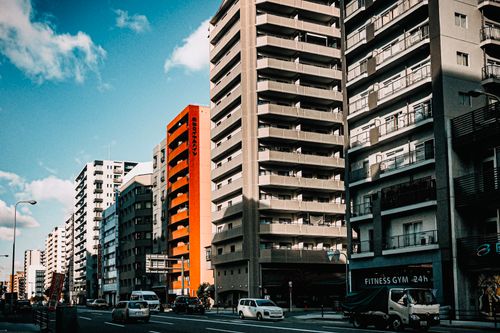 Free Modern high-rise buildings line a bustling urban street under a bright blue sky. Stock Photo