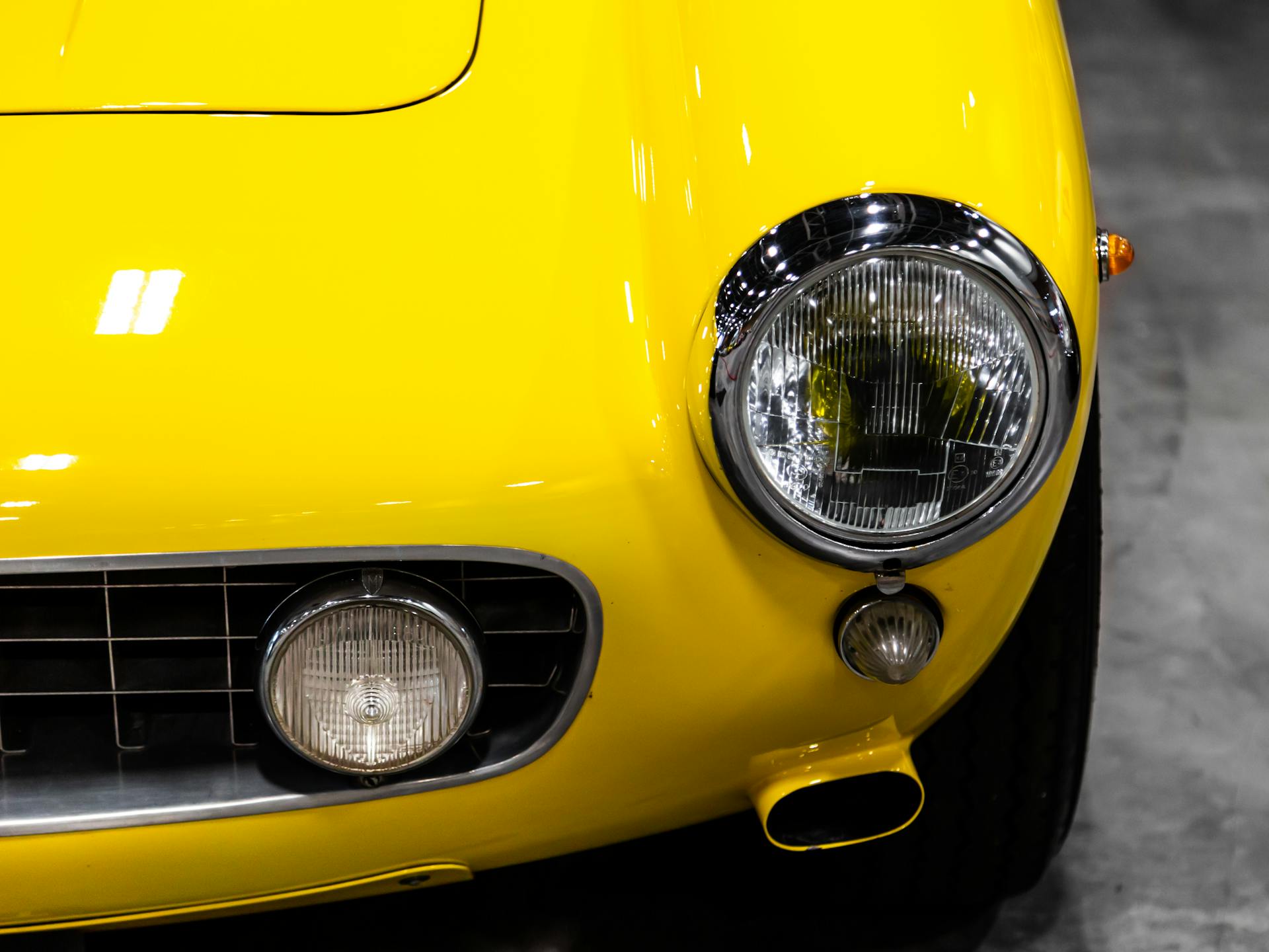 Detailed view of a yellow vintage car's headlight showcasing classic automotive design.