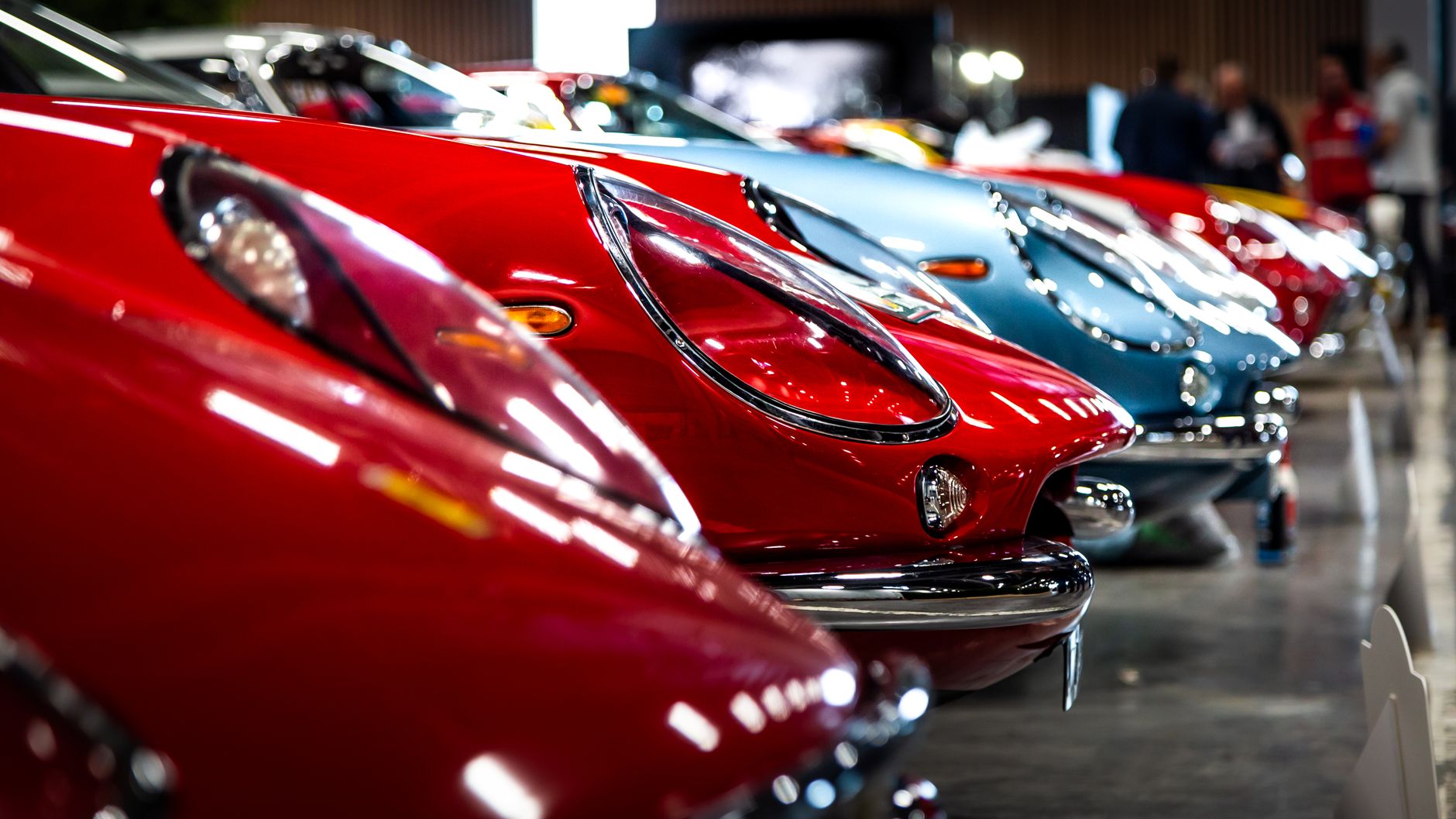 A lineup of vintage sports cars showcased indoors, featuring vibrant colors and classic designs.