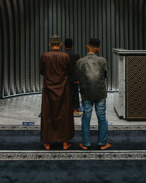 Free Men in prayer at a mosque in Indonesia, showcasing Islamic faith and architecture. Stock Photo