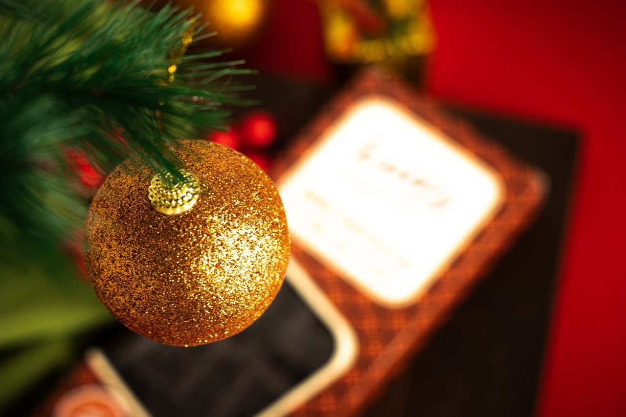 a close up of a sparkling gold christmas ornament hanging on a green t