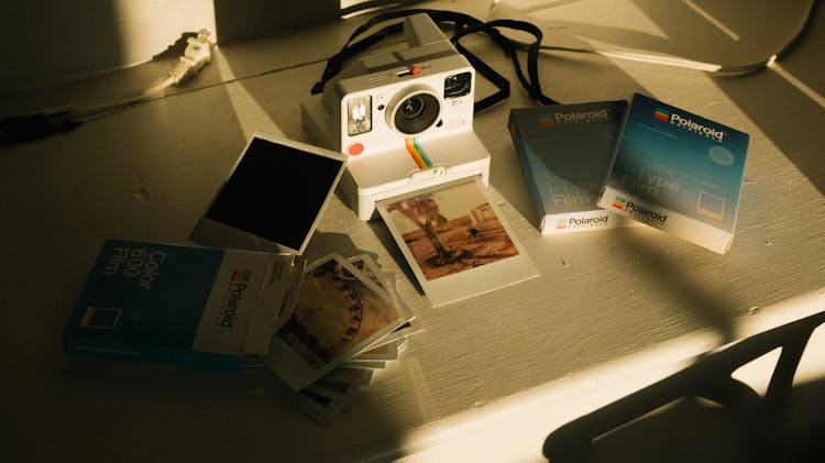 White And Multicolored Polaroid Instant Camera With Pictures