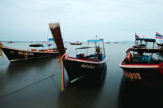 Peaceful scene of traditional longtail boats on a calm Thai shoreline, showcasing local maritime culture.