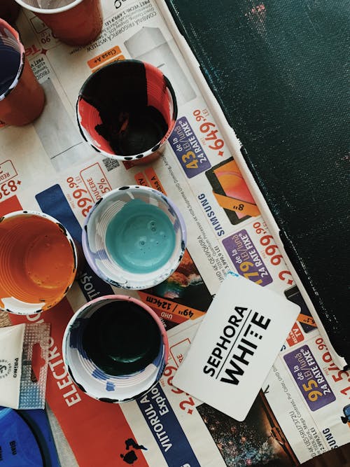 Free Cups With Assorted-color Paints on Newspaper Stock Photo
