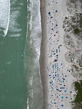 Stunning aerial shot of a lively Florida beach with vibrant umbrellas and clear waves.