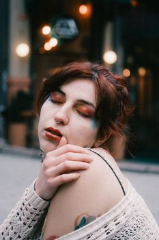 A close-up artistic portrait of a woman with creative makeup outdoors.