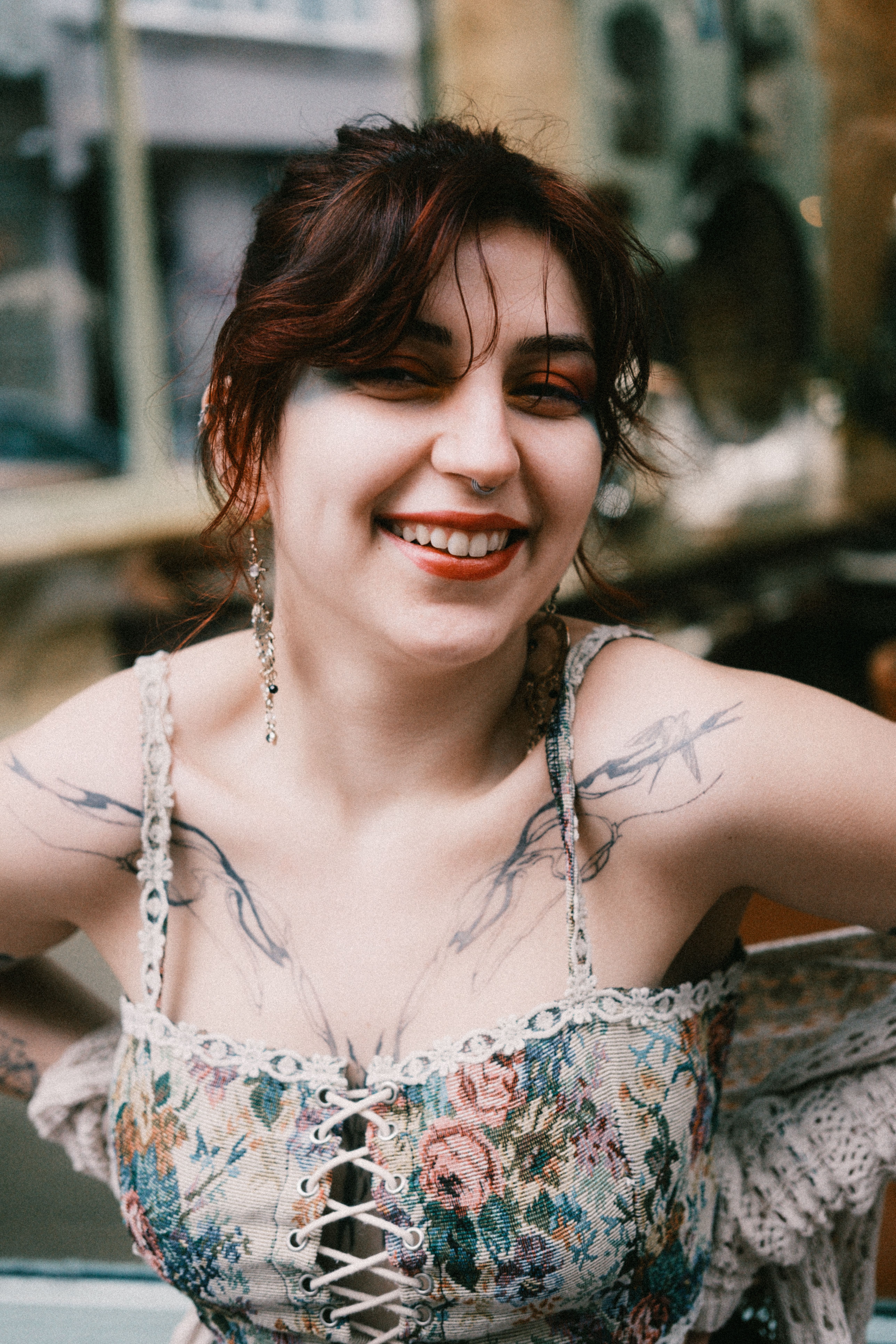 A cheerful woman with tattoos smiling confidently in an urban outdoor setting.