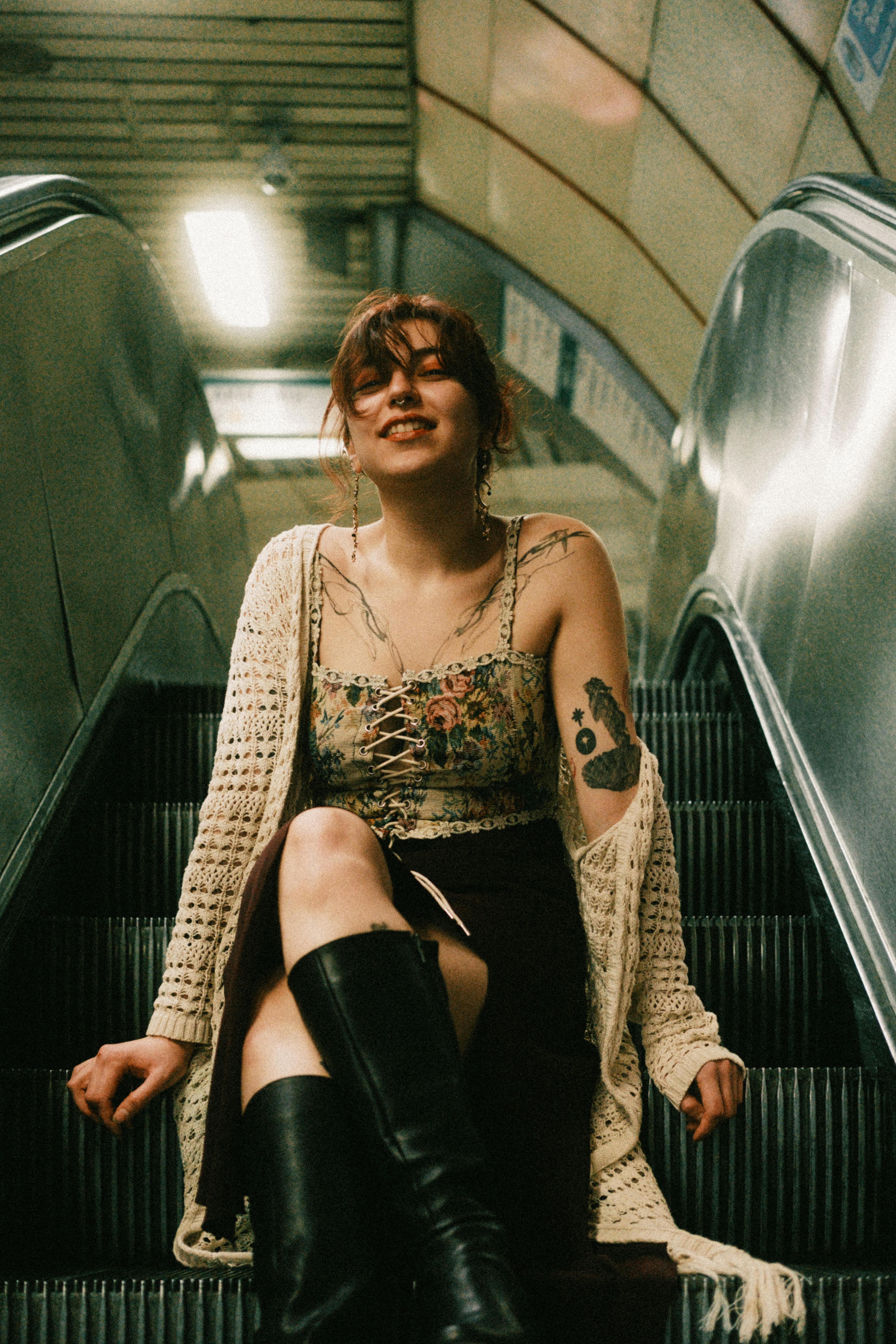 Smiling woman seated on an escalator in a subway station, expressing urban youth culture.