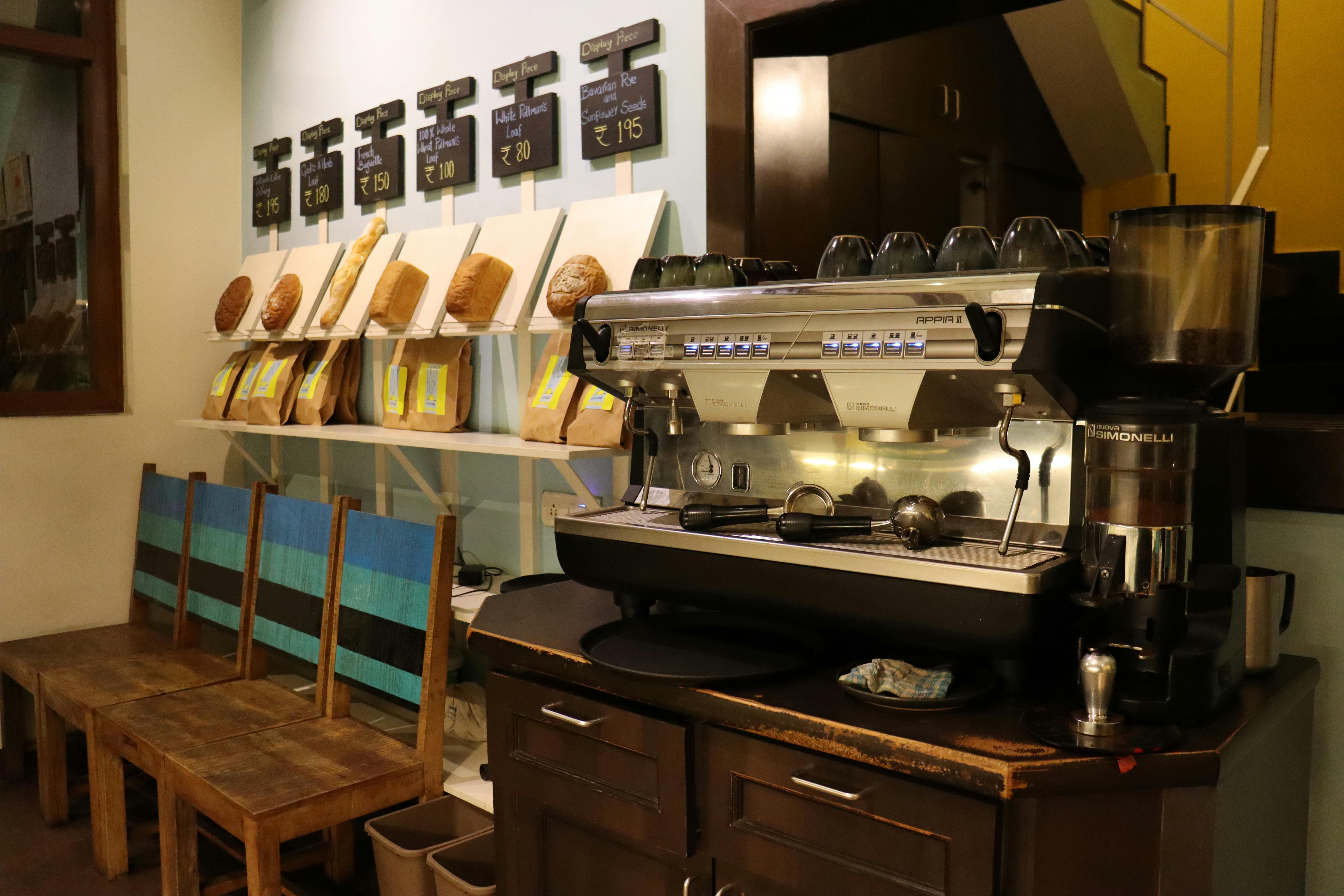 A warm and inviting cafe interior featuring a professional espresso machine and artisan bread display.