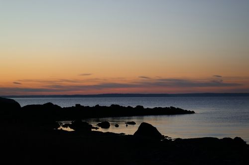 Free A serene sunrise over Cove Island Park with silhouettes of rocks and calm water in Stamford, Connecticut. Stock Photo