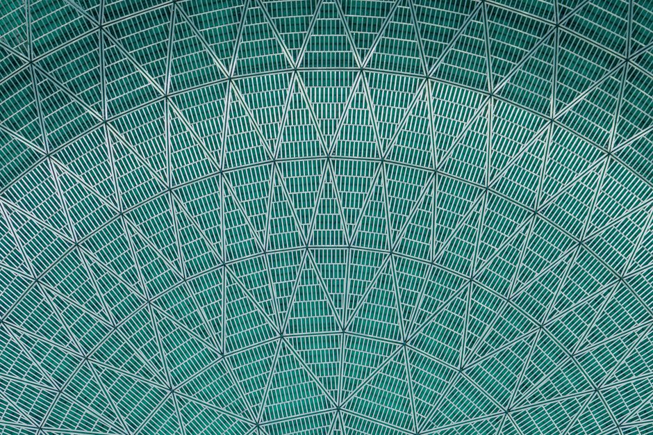 Abstract view of an intricate green geometric ceiling structure with patterned design.