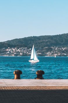 Peaceful sailboat on Vigo Bay with coastal city views in the background, Spain.