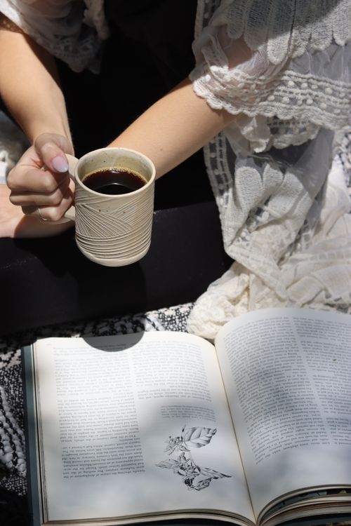 Free Enjoying a peaceful spring morning outdoors with coffee and a book in natural light. Stock Photo