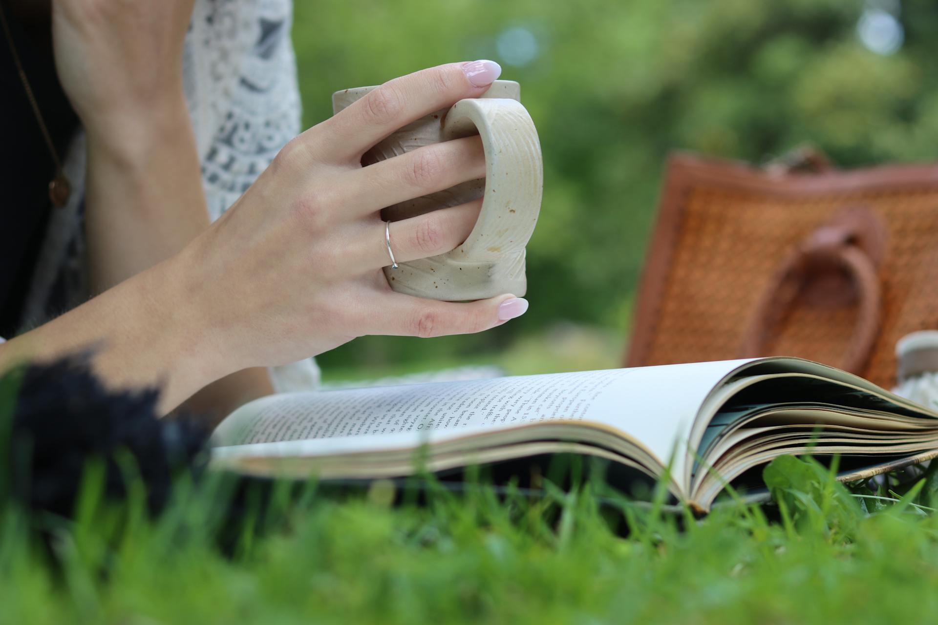 A woman enjoying coffee and a book in a serene outdoor setting.