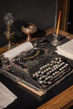 Old Klein Adler typewriter on display with antique lamp and ink pen, evoking nostalgia.