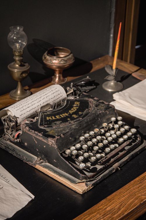 Free Old Klein Adler typewriter on display with antique lamp and ink pen, evoking nostalgia. Stock Photo