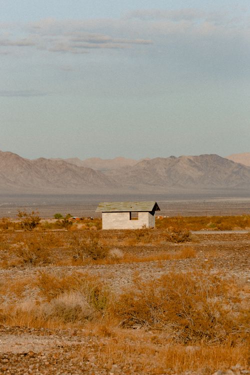 Free A solitary house in an arid desert landscape with distant mountains. Stock Photo