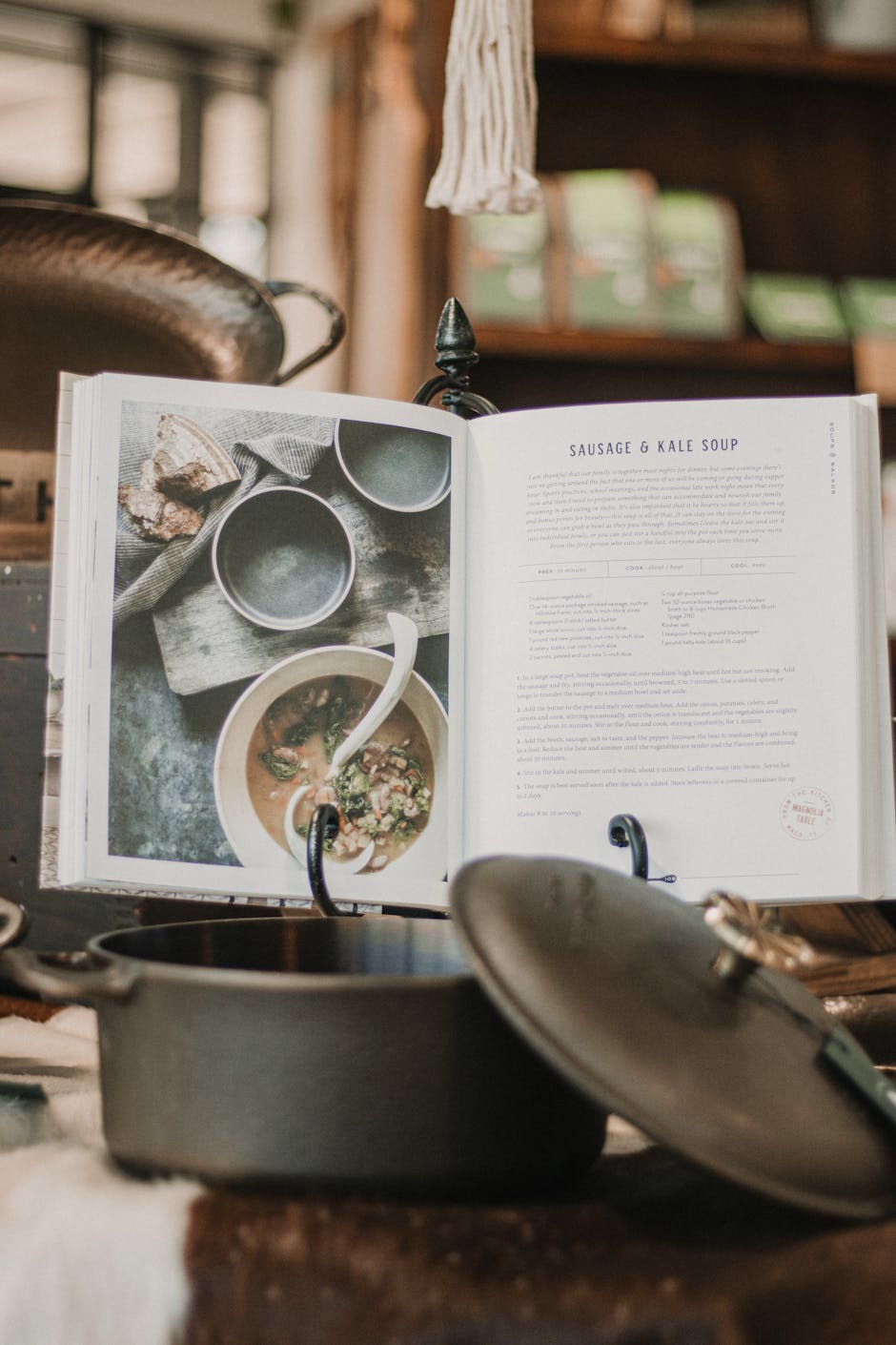 Open cookbook in a kitchen setting with pots, ingredients, and recipes.