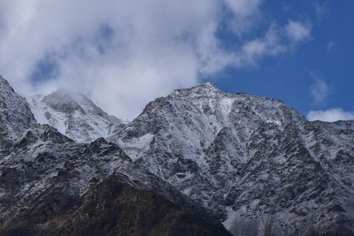 Free Snow-covered mountain range under a blue sky with clouds; winter landscape. Stock Photo