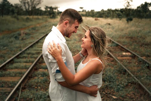 Free Smiling Man and Woman Facing Each Other Beside Railway Train Stock Photo