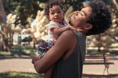 A father joyfully embraces his daughter in a sunny park, capturing a tender moment.