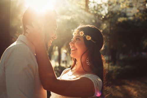 Free A loving couple embracing in a sunlit park during sunset, exuding warmth and happiness. Stock Photo