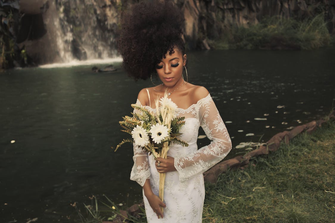 Foto Mujer en un vestido blanco sosteniendo flores de stock gratuita