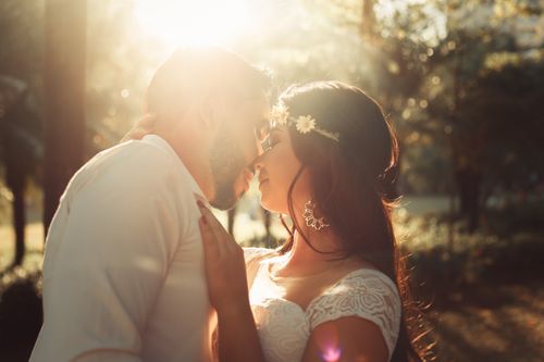 Free A couple shares a tender kiss during their outdoor wedding photoshoot at sunset. Stock Photo