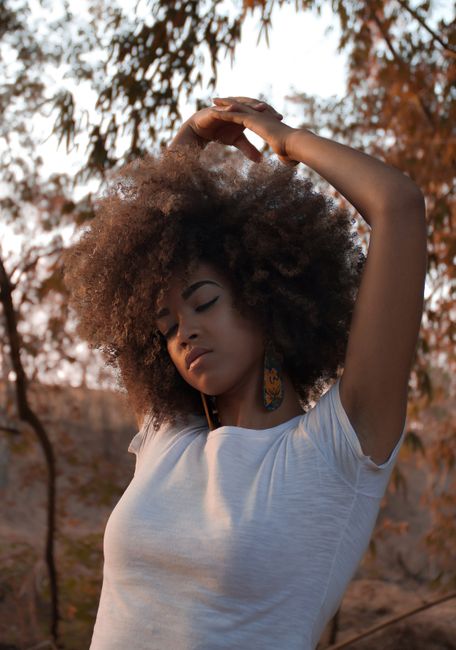 A serene portrait of a woman posing outdoors, embracing natural beauty with eyes closed.