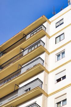 High-angle view of an apartment building's balconies in Ronda, Spain under a clear blue sky.