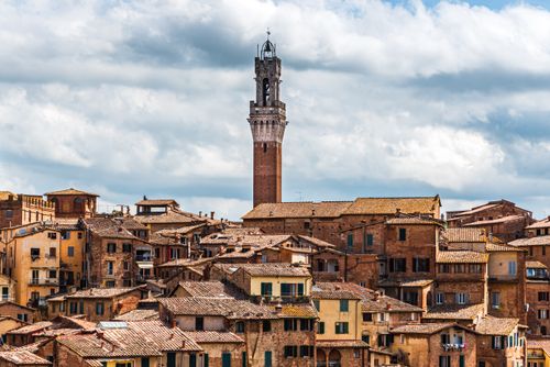 Free Captivating view of Siena's medieval architecture featuring Torre del Mangia under a dramatic sky. Stock Photo