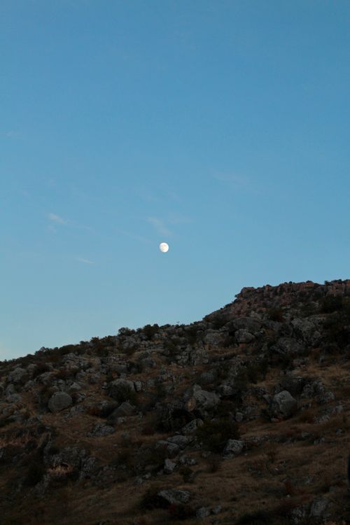 Free A serene twilight landscape with a rocky hillside under a moonlit sky. Stock Photo